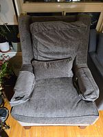 Front view of grey wingback chair displaying cushions and wood legs