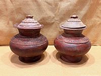 Both terra cotta jars with lids side by side