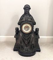 Front view of bronze mantel clock with seated figure, lions, and dial
