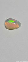 Pear cabochon opal on neutral background showing body tone and play of color