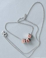 Full view of sterling chain laid out with three copper cube charms