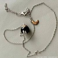 Entire necklace laid out showing chain, glass orb pendant, gold-tone moon charm and clasp