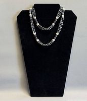 Necklace displayed on black bust showing triple-strand layout
