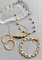 Group shot of two necklaces, hoop earrings and two-tone bracelet