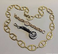 All three items laid out: chain belt surrounding bracelet and charm