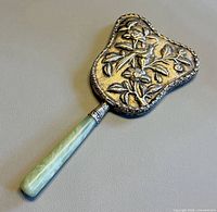 Front view showing embossed bird and floral design and jade handle