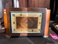Front view of wooden mantel clock showing Art Deco dial missing hands and glass
