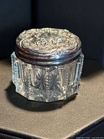 Angle view showing cut glass body and repoussé sterling lid