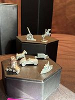 Group view of seven Pewter Monopoly tokens displayed on pedestals