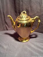 Full view of gilt teapot showing body, spout, lid and foot