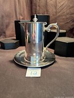 Front view of Wallace silverplate syrup pitcher with attached underplate