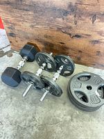 All items together: two assembled adjustable dumbbells, one 25 lb hex dumbbell, stack of four 10 lb plates