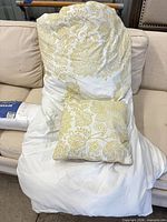 Comforter draped over sofa with matching pillow on top