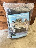 Front of packaged magnetic garage door screen with label showing installed example