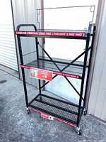 Full view of Coca-Cola rolling display rack showing three shelves, header frame, caster wheels