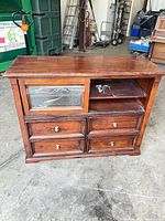 Front view of brown wood cabinet showing drawers, glass door, shelves