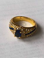 Top view of gold plated ring with blue center stone and rhinestones