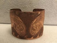 Front view of embossed copper cuff showing mirrored salmon design and overall condition