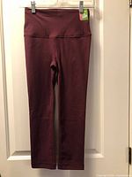 Front view of burgundy Athletic Works fitted crop capri leggings with tag attached