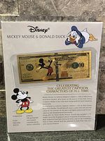 Front of packaged Disney commemorative bill featuring Mickey Mouse and Donald Duck