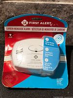 Front view of sealed First Alert carbon monoxide alarm on blister card showing product features and minor packaging wear