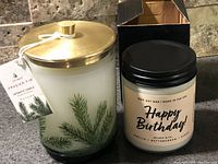 Both candles side by side showing full jars, labels, lids, and Thymes hang-tag