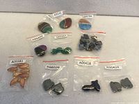 Top view of all nine labeled bags showing cabochons, beads and carved stone pieces