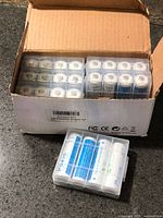 Open box showing multiple plastic cases filled with AA batteries