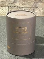 Grey cylindrical gift tube with gold foil text