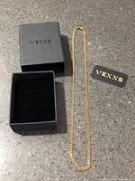 Necklace laid out beside Venns branded box and logo card