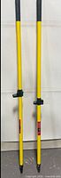 Two yellow fibreglass broom handles standing upright