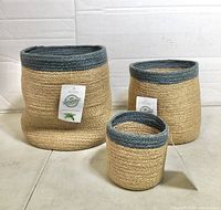 three Alkaso jute baskets standing side by side showing size difference and tags