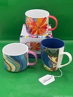Front view of three mugs showing designs and handles