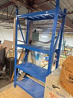 Front angled view of blue metal shelving, four shelves visible
