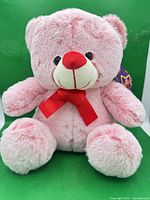Front view of pink teddy bear showing face, bow and overall plush condition