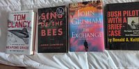 Group shot of four hardcover books: Weapons Grade, Sins of the Bees, The Exchange, Bush Pilot With a Briefcase