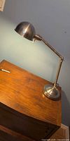 Full view of adjustable metal desk lamp on wooden surface