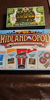 Big Money and Midland-Opoly game boxes side by side
