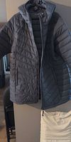 Front view of grey quilted hooded puffer coat hanging, zipper open