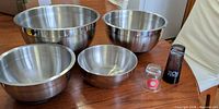 Group shot of four stainless steel mixing bowls and two shot glasses