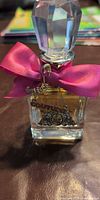 Front view of Juicy Couture perfume bottle showing bow, stopper and charm