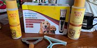 Overview of all grooming items: two Burt’s Bees bottles, clipper kit box, deshedding tool, rake comb