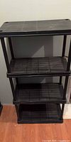 Front view of black 4-shelf plastic unit