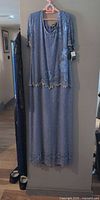 Full view of blue silk evening dress on hanger