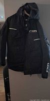 Full view of front of black FXR snowmobile jacket hanging