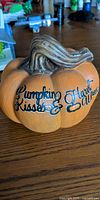 Front view showing text "Pumpkin Kisses & Harvest Wishes" on orange pumpkin with brown stem