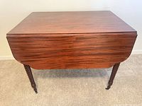 Full view with leaves down showing wood grain, drawer front, barley twist legs on casters