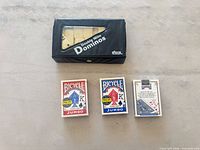 Domino set in closed case beside three Bicycle card decks