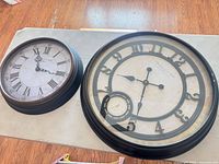 Both wall clocks side by side showing size difference and frame color