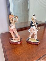 Both clown figurines on wooden bases